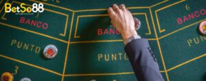 a casino player placing his bet in a baccarat table